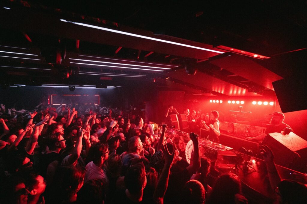 Pista llena de The Bassement Club con la cabina iluminada en rojo